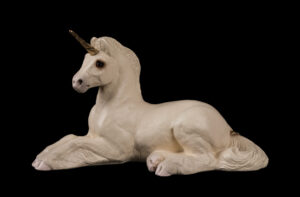 Resting Ponycorn fantasy figurine in White with golden pewter horn, brown glass eyes, and aquamarine-colored jewel. Hand-painted collectible by Windstone Editions.